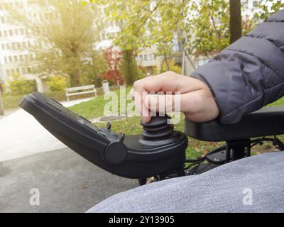 Gros plan d'une personne handicapée en fauteuil roulant électrique conduite main à l'aide de joystick Banque D'Images