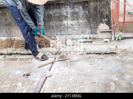 Un homme ramasse un sol dur avec une pioche sur un chantier de construction Banque D'Images