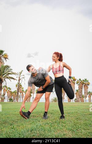 Couple sportif vertical étirant leurs muscles avec des poses de yoga après une séance d'entraînement physique sur la côte. Deux personnes sportives profitant d’une séance de Pilates en plein air pour améliorer leur santé et leur flexibilité. Photo de haute qualité Banque D'Images