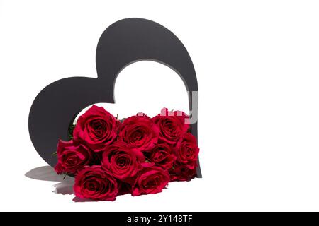 Un groupe de roses rouges vibrantes disposées soigneusement devant une forme de coeur. Les roses sont en pleine floraison, mettant en valeur leur couleur vive. Banque D'Images