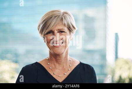 Portrait, femme senior et heureux pour les affaires en ville ou état d'esprit positif pour la carrière ou le travail. PDG, fierté ou sourire et professionnel sur balcon ou Banque D'Images