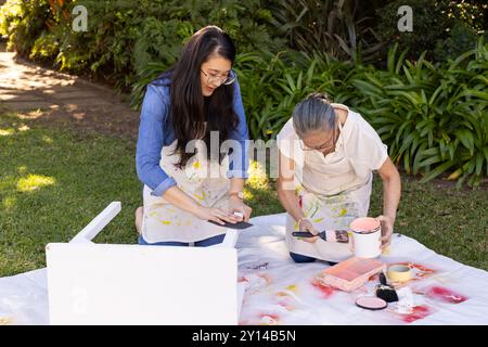 Peindre des meubles à l'extérieur, petite-fille asiatique et grand-mère travaillant ensemble sur le projet de bricolage Banque D'Images