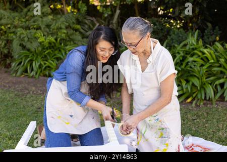 Peindre des meubles ensemble, petite-fille asiatique et grand-mère profitant du projet de bricolage en plein air à gar Banque D'Images