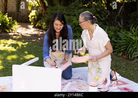 Peindre des meubles ensemble, petite-fille asiatique et grand-mère se lier dans le jardin Banque D'Images