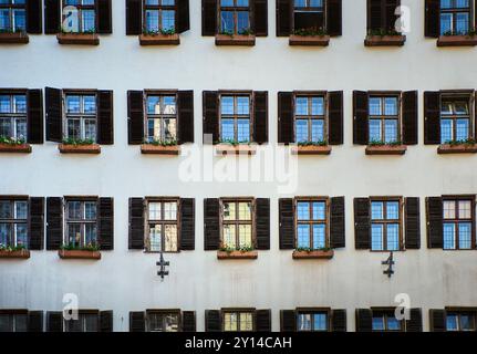 Façade de vieux bâtiment avec motif de vieilles fenêtres ouvertes avec jalousie en bois et fleurs à Innsbruck. Architecture historique ou extérieur médiéval Banque D'Images