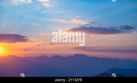 Le soleil couchant sur les montagnes, les beaux rayons du soleil brillent à travers les nuages, le fond naturel, la liberté, la tranquillité et la paix Banque D'Images