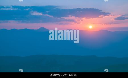 Le soleil couchant sur les montagnes, les beaux rayons du soleil brillent à travers les nuages, le fond naturel, la liberté, la tranquillité et la paix Banque D'Images