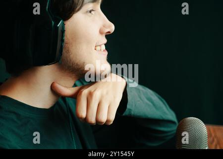 Un jeune homme portant des écouteurs est profondément engagé tout en parlant dans un microphone Banque D'Images