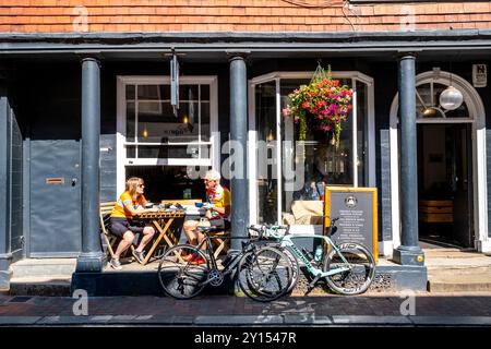 Deux cyclistes seniors assis devant Un café avec Un café, High Street, Lewes, East Sussex, Royaume-Uni. Banque D'Images