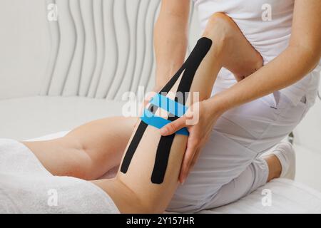 Kinesio taping des membres inférieurs pour prolonger l'effet de massage gros plan, le thérapeute applique du ruban adhésif sur les jambes du patient Banque D'Images