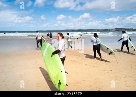 Un groupe d'apprenants novices de surf débutant une leçon de surf avec l'école de surf SSS sur Towan Beach à Newquay en Cornouailles au Royaume-Uni. Banque D'Images