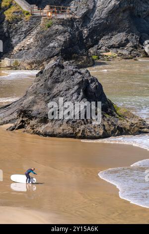 Un surfeur solitaire se préparant pour une séance de surf sur GT Great Western Beach à Newquay en Cornouailles au Royaume-Uni. Banque D'Images