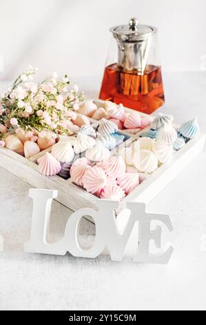 boîte de petite meringue artisanale colorée sur la table. fleurs de meringue faites à la main préparées pour offrir en cadeau. Doux cadeau romantique. Mot d'amour. Banque D'Images