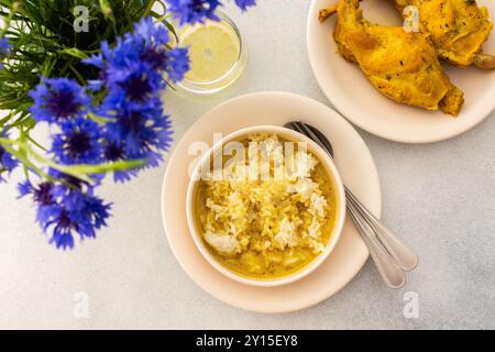 Ragoût de lapin avec du riz, du brocoli et des gâteaux de riz, une table servie avec de la nourriture et un vase de fleurs, un délicieux déjeuner copieux ou dîner Banque D'Images