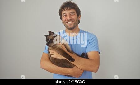 Un jeune homme souriant tenant un chat siamois sur un fond blanc Banque D'Images