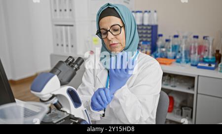 Une femme scientifique portant le hijab met des gants dans un laboratoire, symbolisant les soins de santé, la recherche et la diversité. Banque D'Images