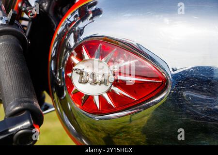 Gros plan d'un réservoir de carburant de moto BSA vintage avec une finition chromée brillante et des accents rouges, reflétant l'environnement. Banque D'Images