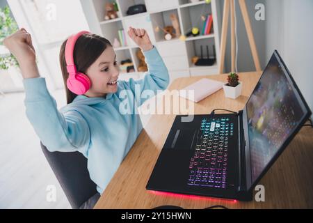 Photo de joyeux mignon jolie fille porter casque gamer à l'aide d'un gadget jouant à un jeu vidéo en ligne Banque D'Images