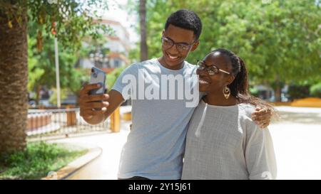 Mère et fils prenant selfie ensemble dans un parc urbain, affichant l'amour et le bonheur en plein air, cadre urbain Banque D'Images