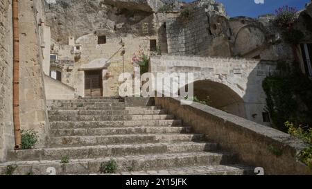 Escalier en pierre menant à une façade de bâtiment antique dans la ville historique de matera, basilicate, italie, europe, entouré de structures rocheuses et flowe Banque D'Images