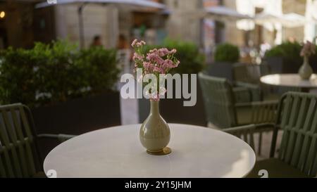 Une table de café en plein air magnifiquement placée dans une rue des pouilles, en italie, mettant en vedette un délicat bouquet de fleurs roses italiennes statice dans un vase avec c confortable Banque D'Images