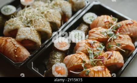 Délicieux assortiment de sushis servi sur une table en béton présentant des rouleaux de saumon frais, du maki enveloppé de nori et des rouleaux californiens nappés de sésame Banque D'Images