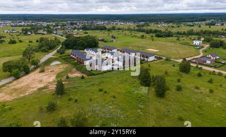 Vue aérienne d'un quartier résidentiel avec des maisons modernes entourées de champs verdoyants et d'arbres. Le paysage présente un mélange d'espace développé et naturel Banque D'Images