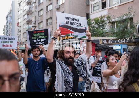 Un activiste marche avec une pancarte disant "pas de port pour le génocide" pendant le rassemblement. Les partis politiques et les organisations de la société civile se sont réunis à Izmir pour protester contre l’amarrage du navire d’assaut amphibie américain « USS Wasp », chargé de protéger Israël, dans le port d’Izmir. Cette action est d'une grande importance pour le soutien de la Palestine et du peuple du moyen-Orient, y compris ceux qui veulent se tenir aux côtés de la Palestine. Le navire transportant la mort en Palestine a été invité à quitter immédiatement la Turquie. (Photo Murat Kocabas/SOPA images/Sipa USA) Banque D'Images