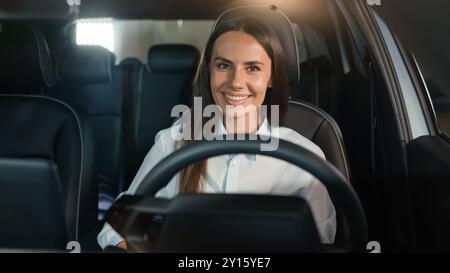 Femme caucasienne fille femme conducteur assise dans la voiture de location à l'intérieur dans l'automobile souriant heureux à la conduite de caméra profiter de l'achat de nouveau véhicule de transport automatique Banque D'Images