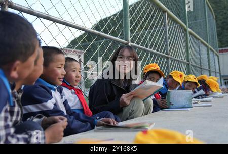 (240905) -- NYINGCHI, 5 septembre 2024 (Xinhua) -- Un enseignant bénévole de l'Université normale de Lingnan dans le Guangdong aide les élèves à revoir les leçons de l'école primaire centrale du canton de Nyangpo, comté de Gongbo'Gyamda, ville de Nyingchi, région autonome de Xizang, au sud-ouest de la Chine, 3 septembre 2024. Située à une altitude de près de 4 000 mètres, l'école primaire a été confrontée à de graves difficultés lors de sa création en 1994, avec des installations pédagogiques médiocres et une rotation des enseignants en hausse. Pour aider à résoudre ces problèmes et améliorer l'éducation locale, les écoles de la ville de Zhongshan, province du Guangdong du sud de la Chine, organe Banque D'Images