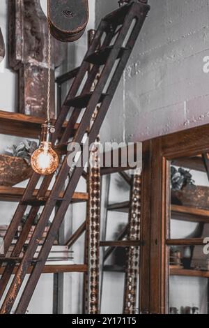 Vieille échelle en bois vieilli contre mur blanc entouré de miroirs au magasin de style Farmhouse Banque D'Images
