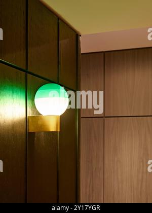 Détail de revêtement en bois avec applique murale lumineuse. Woolyard, Londres, Royaume-Uni. Architecte : Conran & Partners, 2022. Banque D'Images