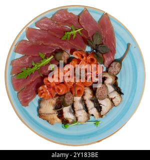 Plateau de fruits de mer gastronomique avec sashimi, roses de saumon et garnitures gastronomiques sur une assiette bleue élégante. Banque D'Images