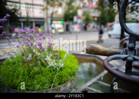 Fontaine d'eau potable publique vintage en métal et en pierre dans une ville européenne. Journée d'été ensoleillée, gros plan, plan grand angle, faible profondeur de champ, pas de poo Banque D'Images