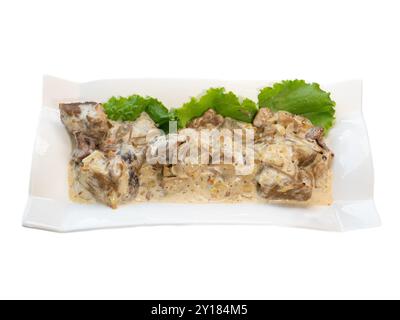 Bœuf Stroganoff crémeux avec laitue fraîche sur un élégant plateau blanc. Banque D'Images