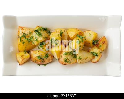 Pommes de terre rôties rustiques aux herbes fraîches sur une élégante assiette blanche. Banque D'Images