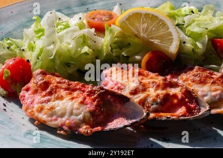 moules cuites au four avec du caviar masago et du fromage sur une assiette blanche avec du citron Banque D'Images