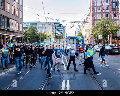 Stockholm, Suède - 24 août 2024 : un groupe de personnes arborant des drapeaux suédois manifestent en faveur des valeurs occidentales et contre l'islam à Hamngatan in Banque D'Images