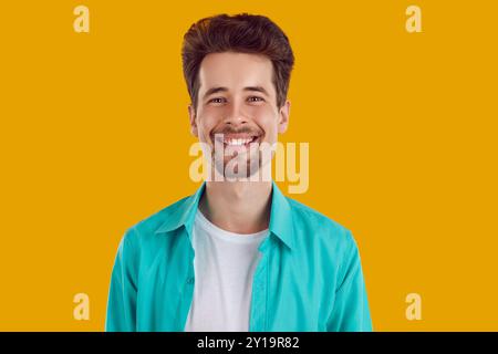 Heureux jeune homme avec un beau sourire large sincère isolé sur fond orange. Banque D'Images