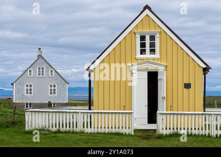 Maison jaune qui habite la plus ancienne et la plus petite bibliothèque en Islande avec une porte ouverte et une clôture blanche. Flatey, Breiðafjörður, Westfjords, Islande Banque D'Images