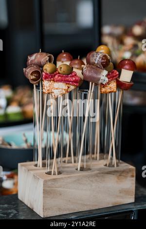 Tableau exquis de hors-d'œuvre gourmands brochés sur un élégant support en bois. Banque D'Images