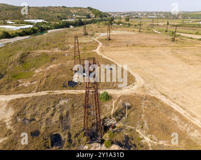 Vieux champ de prise de pompe de puits de pétrole rouillé à Albaina, drone aérien images dans la journée ensoleillée. Minuscules pompes à huile maison sur les Balkans Banque D'Images