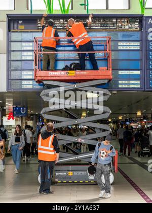 Techniciens travaillant sur un tableau d'information électronique, tableau d'affichage pour les liaisons ferroviaires à la gare centrale de Düsseldorf, NRW, Allemagne Banque D'Images