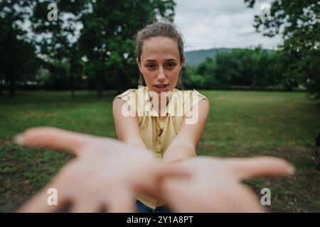 Jeune femme tendre la main dans le parc, moment expressif et émotionnel Banque D'Images