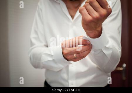 Préparation élégante : homme ajustant le poignet de chemise blanche Crisp pour l'occasion formelle. Banque D'Images