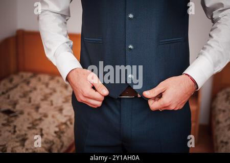 Gilet de costume bleu marine élégamment habillé en boutonnage pour homme dans une chambre confortable. Banque D'Images