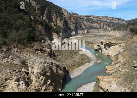 Une rivière claire coule à travers une gorge rocheuse entre des montagnes envahies par la végétation sous un ciel bleu, Parc naturel Noguera Ribagorcana Mont-Rebei, montagne Montsec Banque D'Images