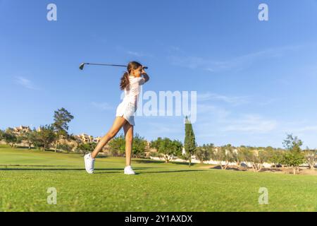 Photo horizontale pleine longueur avec espace de copie d'une jeune femme blonde caucasienne jouant au golf dans un parcours vert balançant Banque D'Images