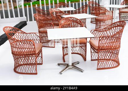 Patio confortable avec des tables en bois entourées de chaises, parfait pour les repas en plein air et la détente Banque D'Images