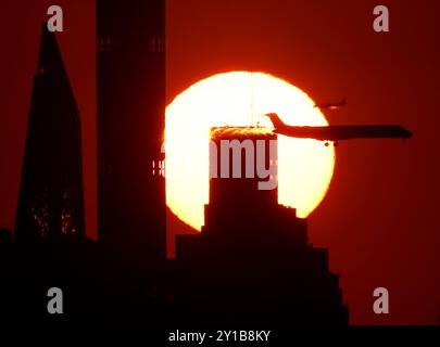 Flushing Meadow, États-Unis. 05th Sep, 2024. Les avions passent devant le soleil se couchant derrière les gratte-ciel de Manhattan depuis le sommet du stade Arthur Ashe lors des US Open Tennis Championships 2024 au USTA Billie Jean King National Tennis Center le jeudi 5 septembre 2024 à New York. Photo de John Angelillo/UPI crédit : UPI/Alamy Live News Banque D'Images